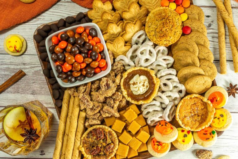 Fall dessert board filled with mini pies, cookies, candies, caramel, and pretzels.