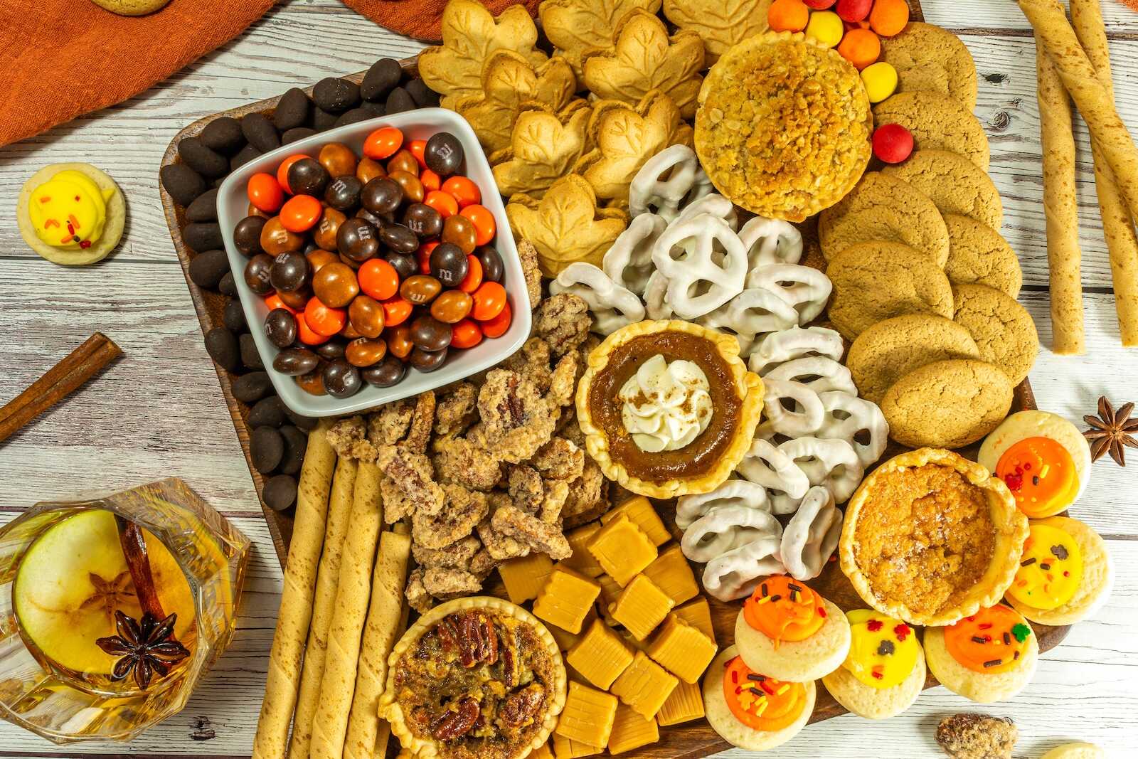Fall dessert board filled with mini pies, cookies, candies, caramel, and pretzels.