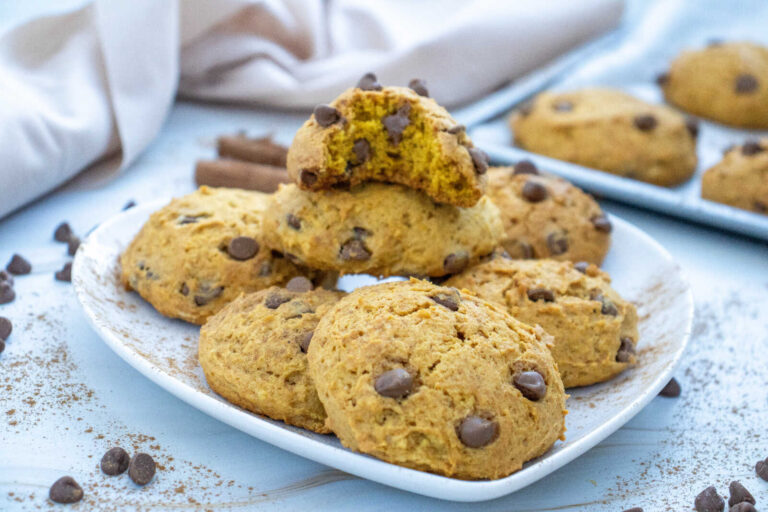Soft pumpkin chocolate chip cookies on a plate with a broken cookie showing inside
