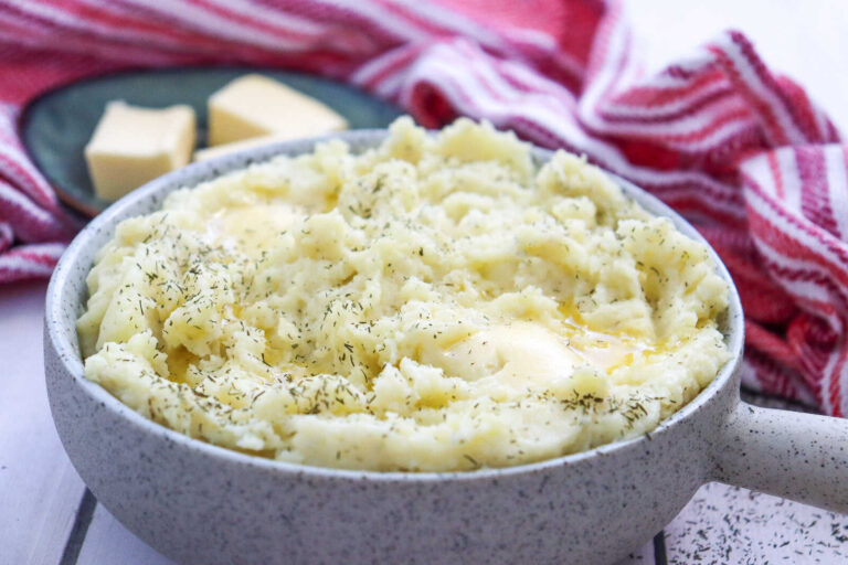 Creamy mashed potatoes with butter and herbs in a bowl.